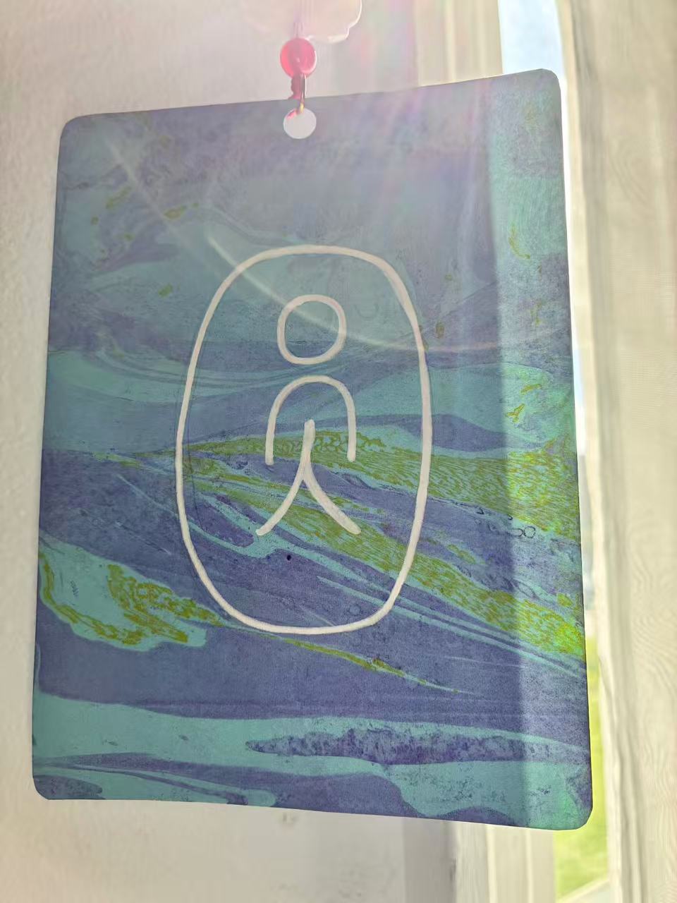 A blue hand-painted card with the Chinese character yuan hanging in sunlight
